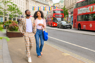 Couple walkig along Regent Street's infamous curved street, with red double decker buses in the background 